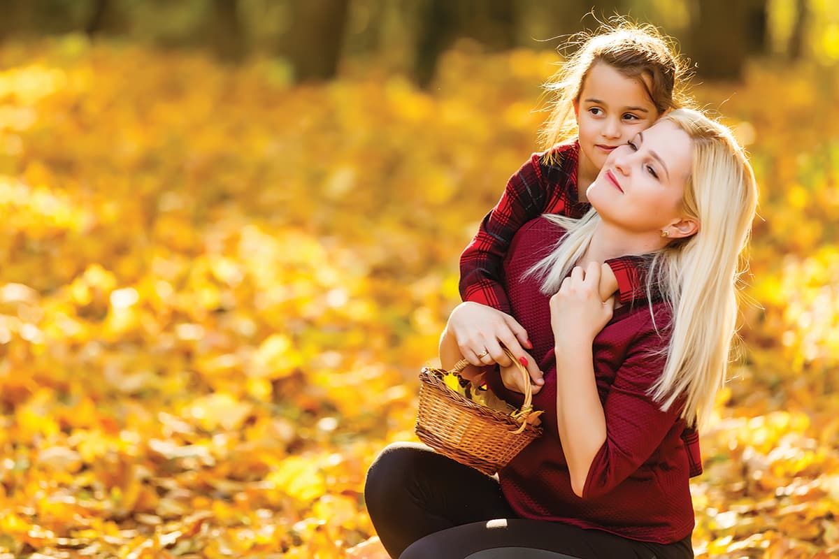 Mom and daughter collecting fall leaves