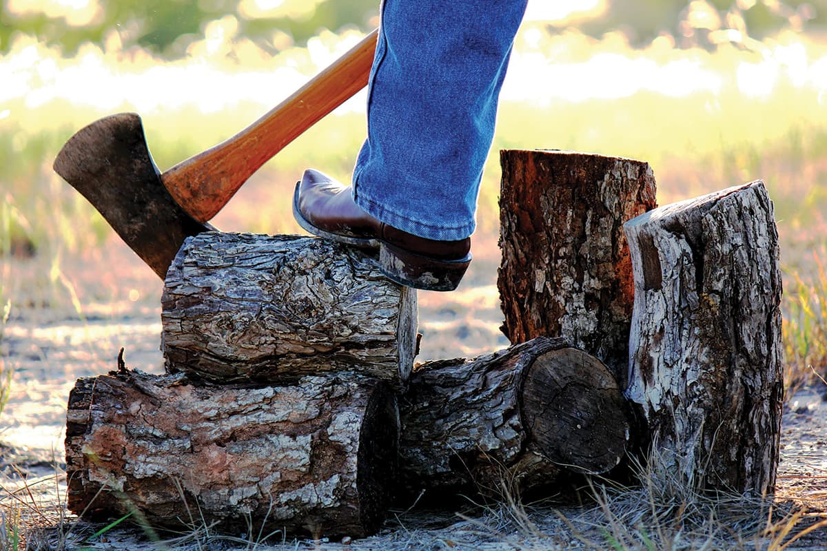 Man with boots and axes standing on firewood