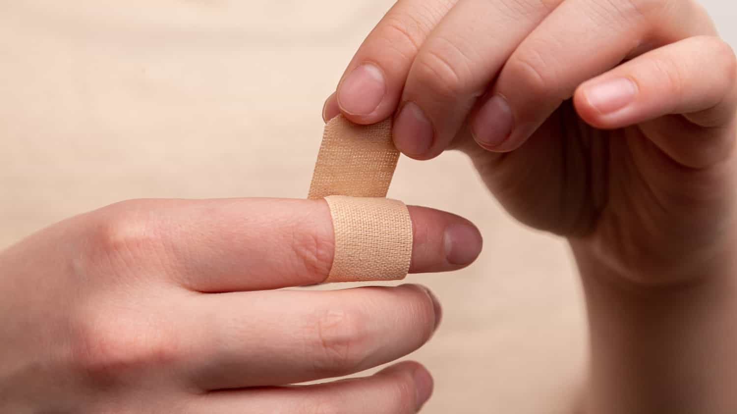 person wrapping bandage around finger